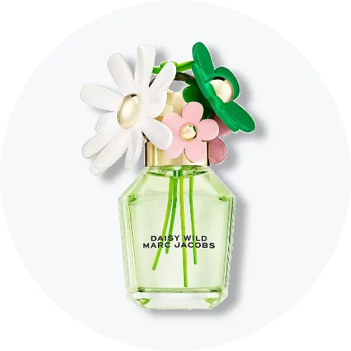 Her ses Marc Jacobs Daisy Wild i en transparent parfumeflakon med lysegrønt indhold. Flakonen er dekoreret med store blomster i hvid, grøn og rosa på låget, og teksten “Daisy Wild Marc Jacobs” står på forsiden. Produktet står centralt mod en lys, rund baggrund.