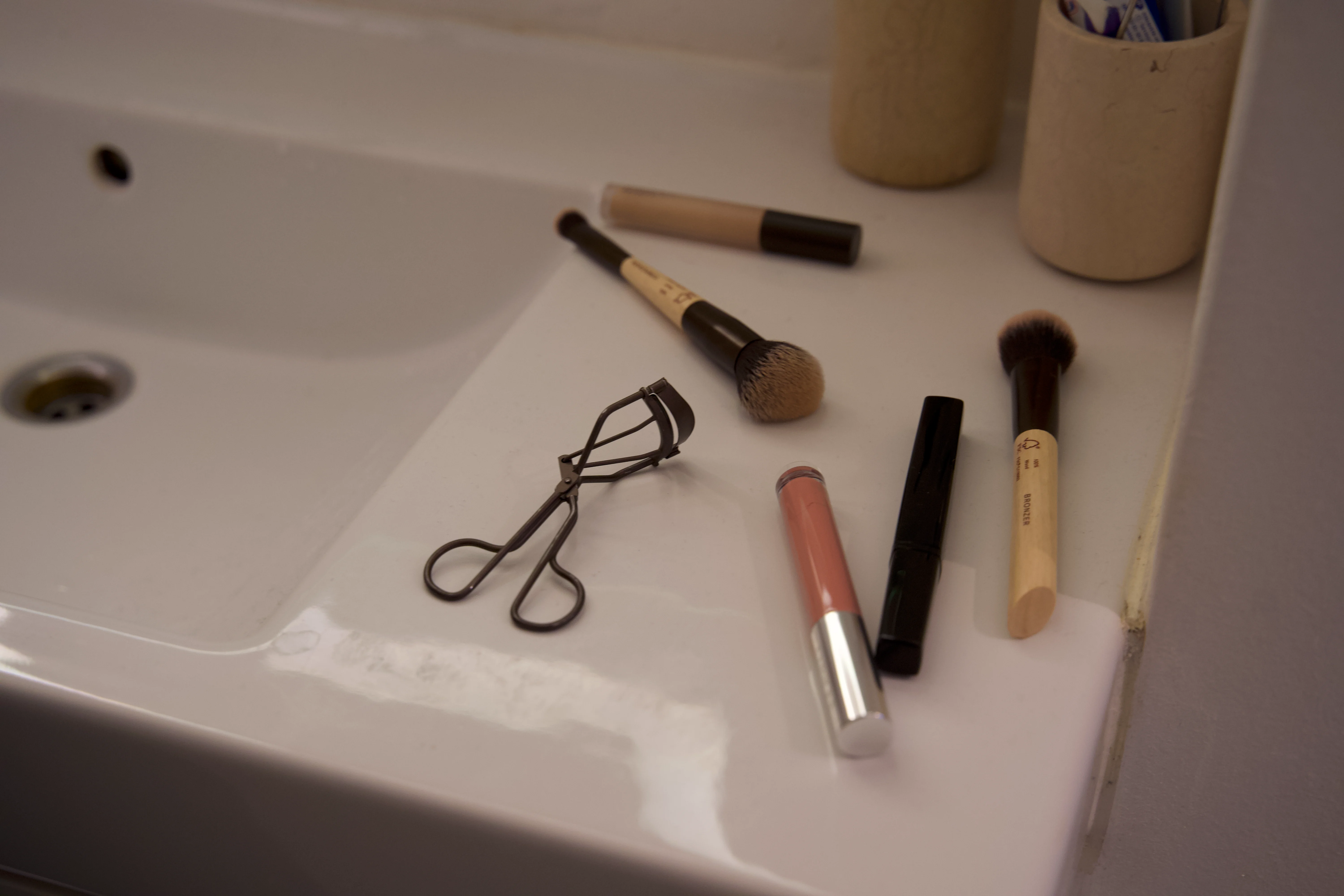 Makeup og makeup børster ligger på en håndvask.