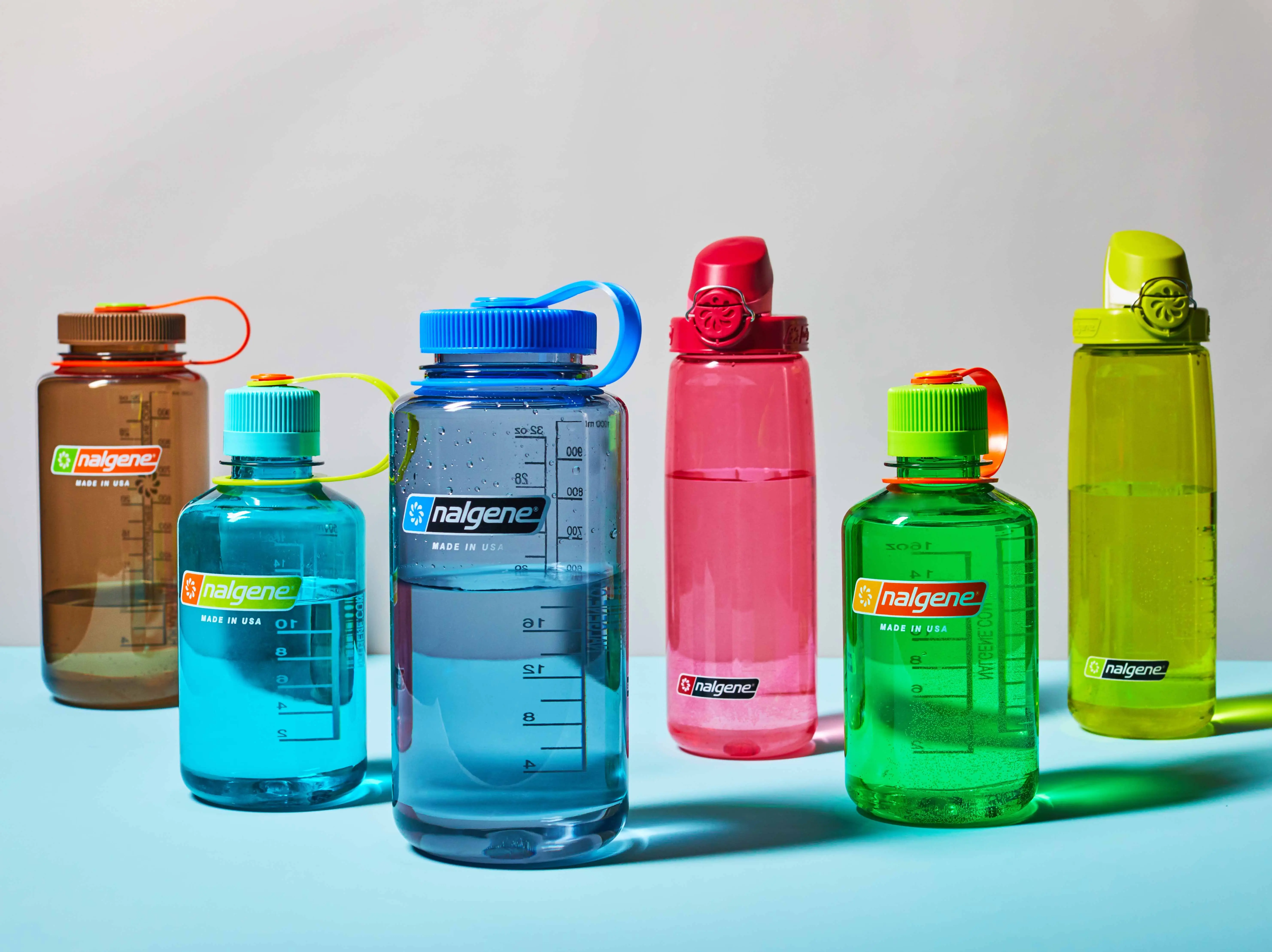 Seks farverige Nalgene vandflasker i forskellige størrelser med målestreg og 'nalgene MADE IN USA' logoer.