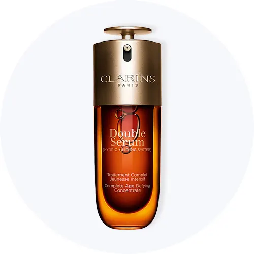 Her ses Clarins Double Serum i en brun og guldfarvet flaske på en lysegrå cirkel.