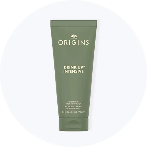 Her ses Origins Drink Up Intensive Overnight Hydrating Mask i en grøn tube på en lysegrå cirkel.