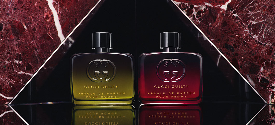 Her ses to Gucci guiltu parfumer ved siden af hinanden. En gul og en rød på en baggrund af rød marmor.