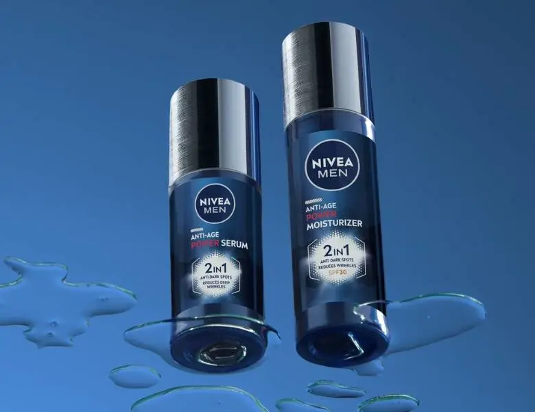 Her ses en blå baggrund med to mørkeblå og grå Nivea produkter. Billedet er taget skråt nedefra.