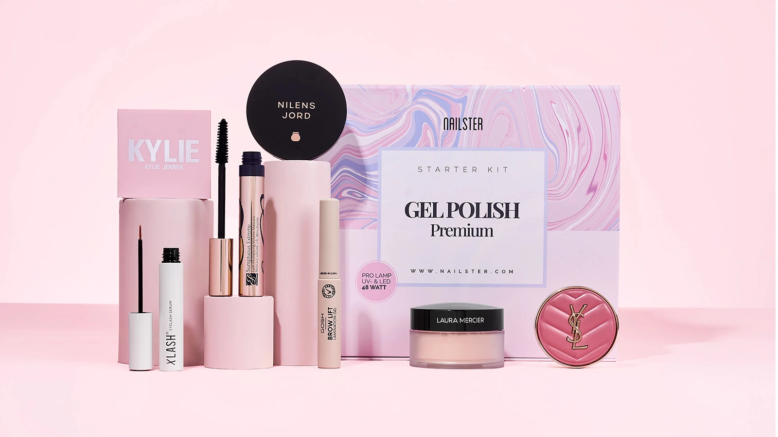 Et Nailster Gel Polish startsæt, mascara, øjenvippeserum, bryngel og pudder på en lyserød baggrund.
