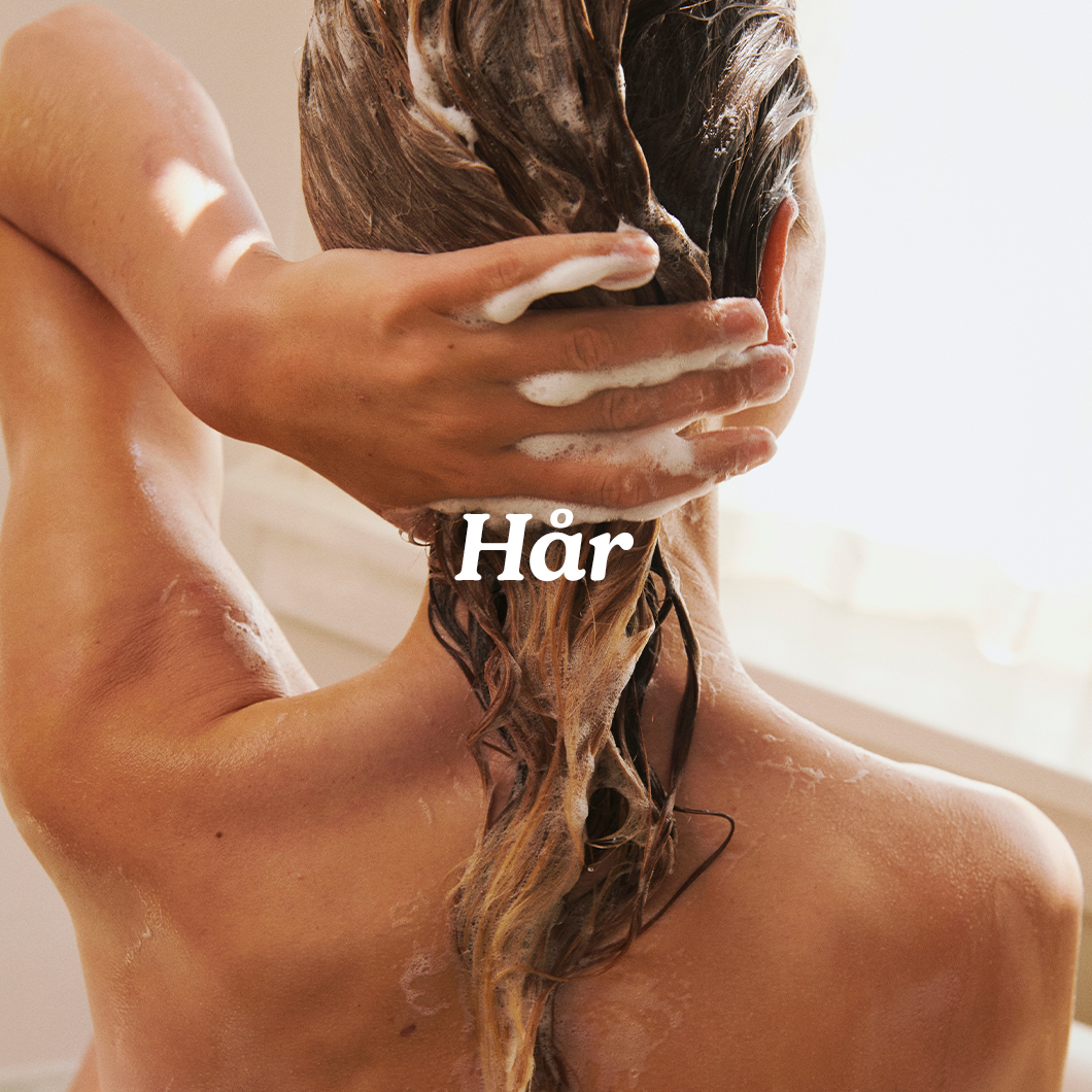 Her ses en person, der vasker hår med skum i badet med teksten “Hår”.