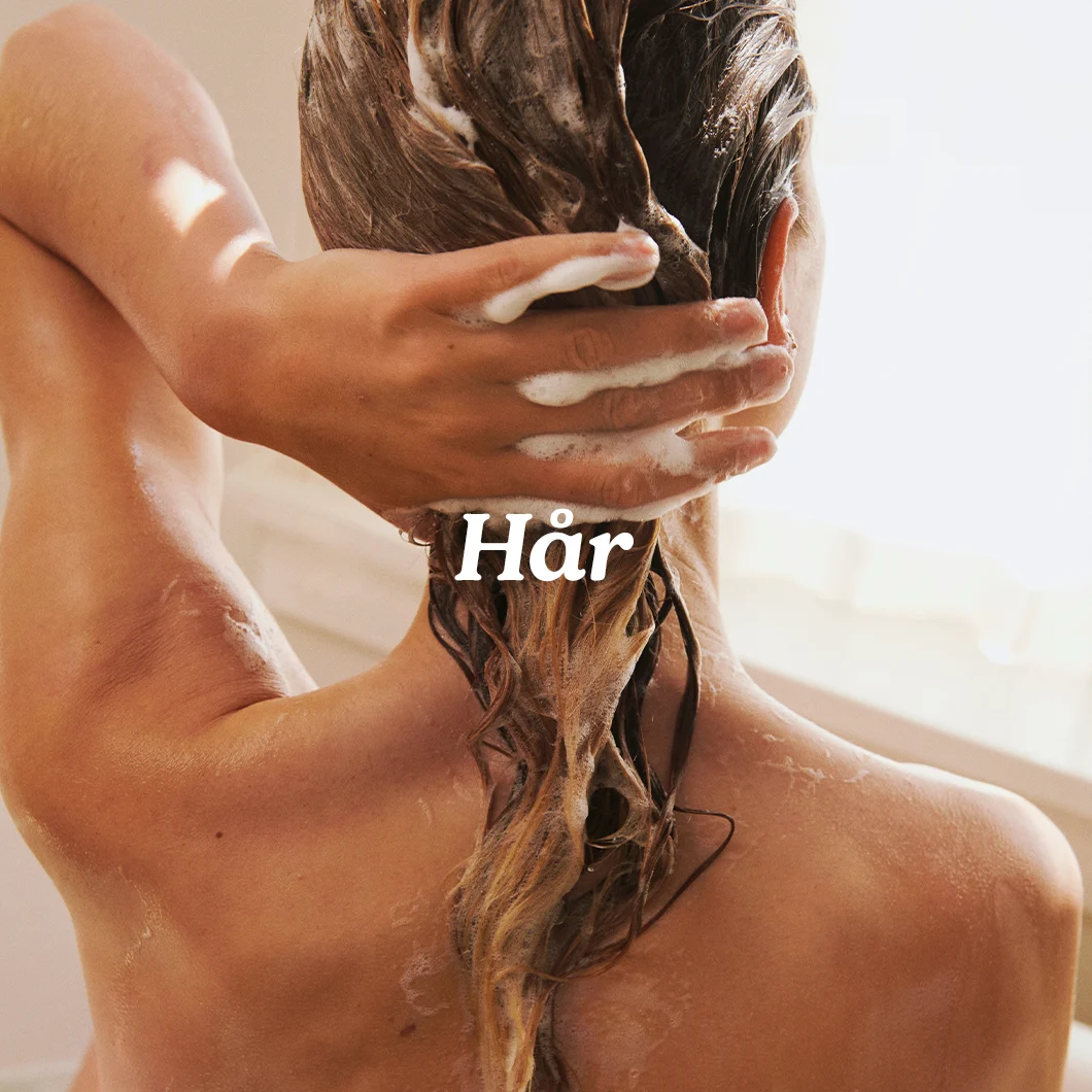 Her ses en person, der vasker hår med skum i badet med teksten “Hår”.