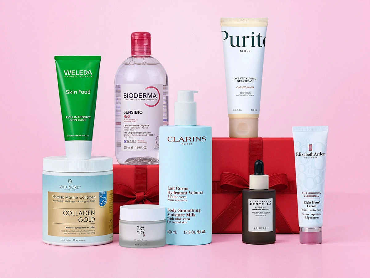 Et udvalg af hudplejeprodukter fra forskellige mærker, som Weleda og Bioderma, præsenteret med røde gaveæsker.
