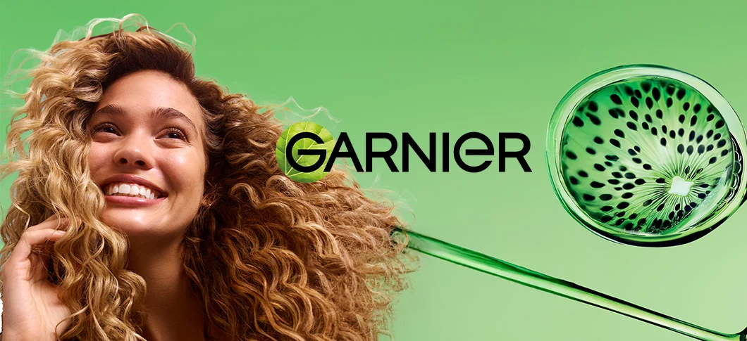Garnier-reklame: En smilende kvinde med krøllet hår og et kiwi-design i grøn væske.