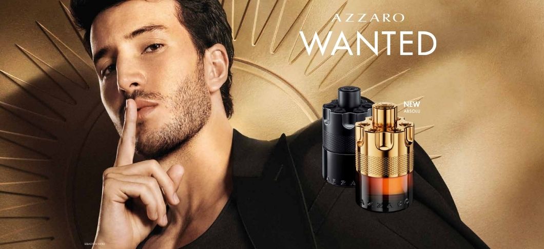 Her ses et billede med en person til venstre mod en gylden baggrund samt to parfumeflakoner til højre. Øverst står teksten “AZZARO WANTED”, og ved produkterne står “NEW ABSOLU”. Flakonerne er i sorte og gyldne nuancer.