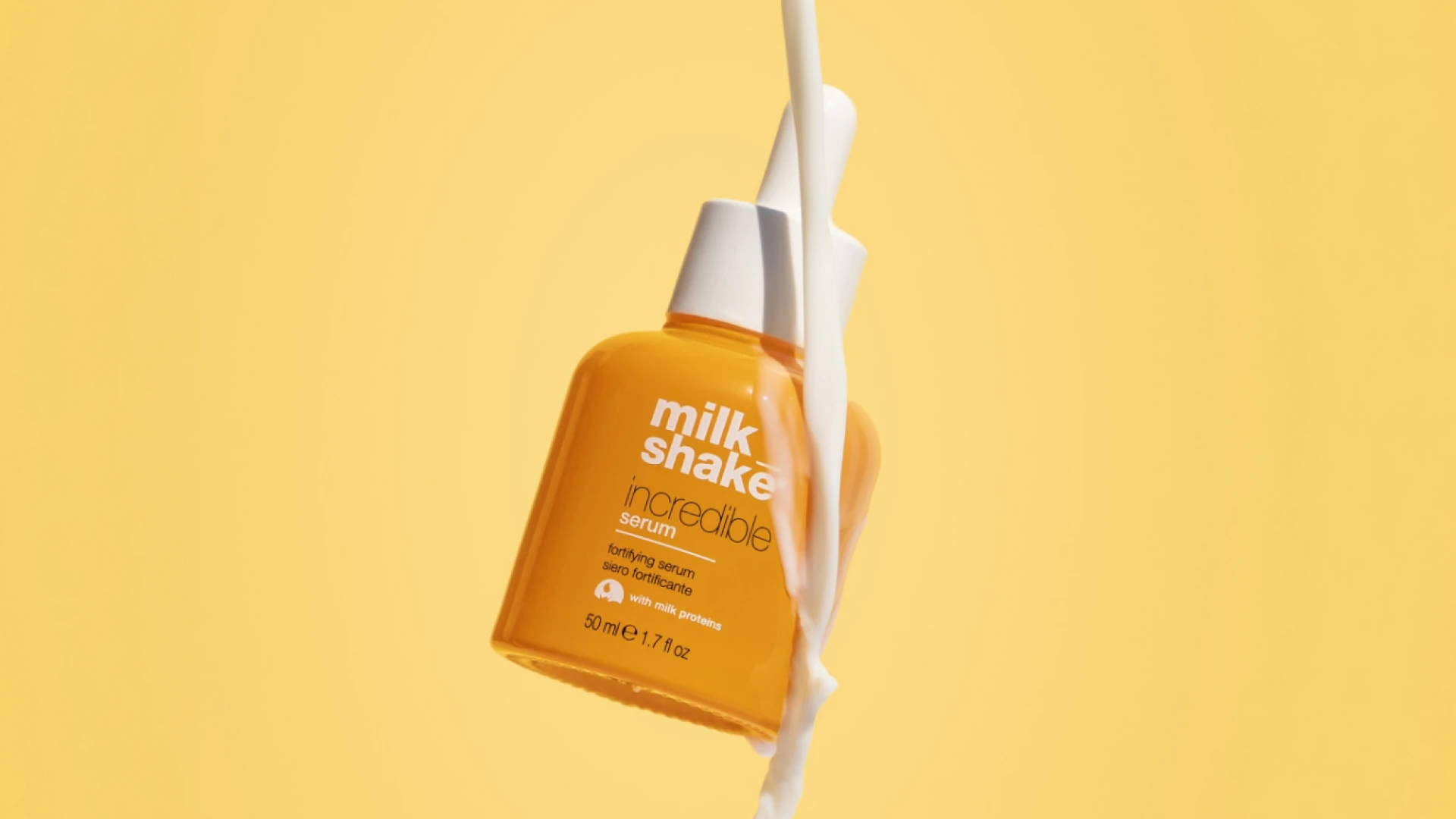 Her ses to milk_shake Moisture & More Serum i orange flasker med hvide pumper, omgivet af vandstænk mod en hvid baggrund.