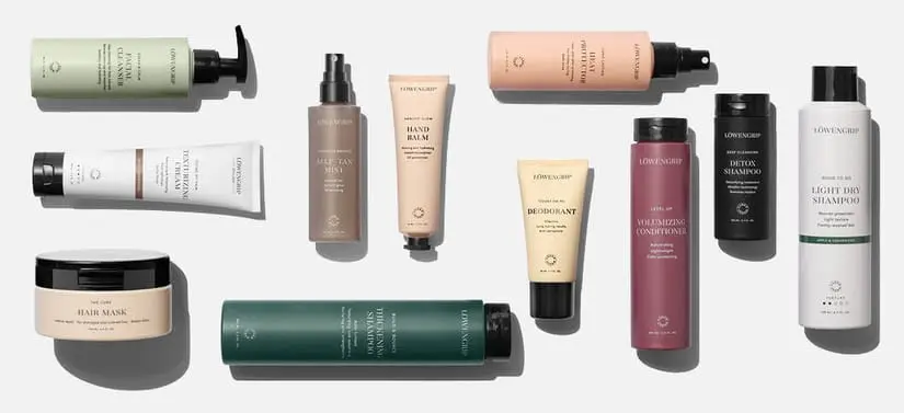 Her ses et billede med flere hår- og kropsplejeprodukter fra Løwengrip placeret spredt mod en lys baggrund. Produkterne inkluderer blandt andet “Detox Shampoo”, “Light Dry Shampoo”, “Deodorant”, “Hand Balm” og “Hair Mask”. Produkterne er i forskellige farver som grøn, beige, rosa og sort med ensartet design.