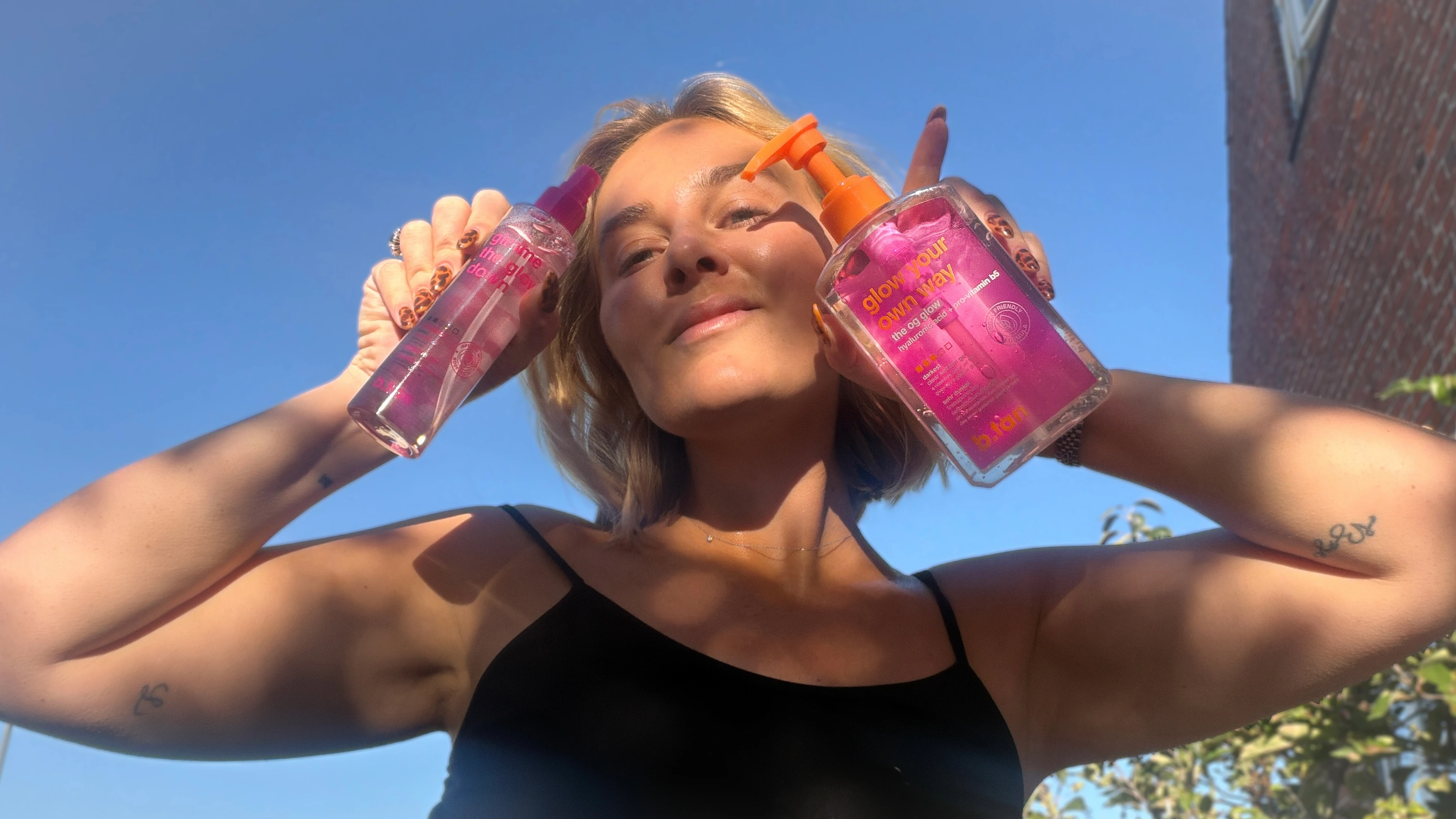 En person holder to lyserøde 'glow your own way': 'gimme the glow down' spray og 'the og glow' pumpe.
