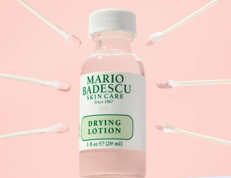 Her ses en lyserød baggrund med et Mario Badescu produkt i midten. Ved siden af ses en vatpind og tre pletter med produktet.