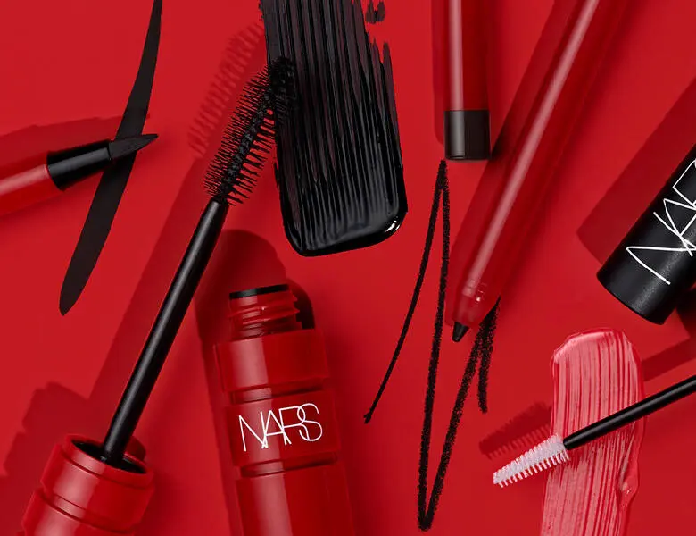 Her ses en rød baggrund med mange forskellige øjenprodukter fra Nars. 