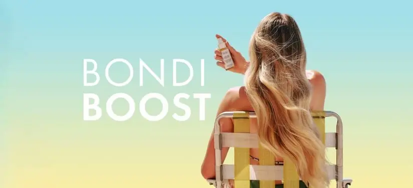 Her ses et billede af en person set bagfra, siddende på en stol mod en gradient baggrund i blå og gul. Personen holder et lille produkt op i hånden. Til venstre i billedet står teksten “BONDI BOOST”.