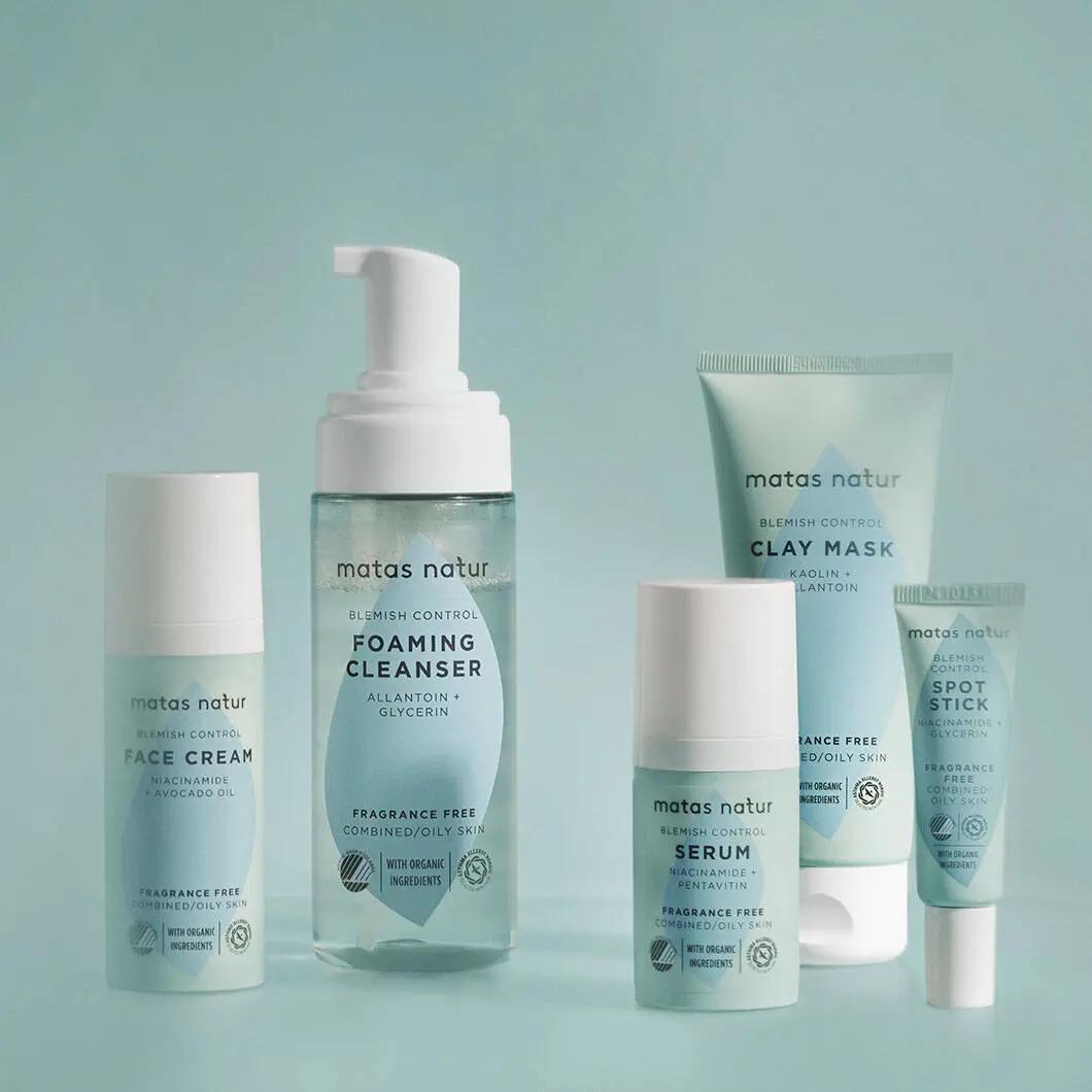 Fem Matas Natur Blemish Control hudplejeprodukter står samlet mod en lyseblå baggrund: ansigtscreme, foaming cleanser med pumpe, serum, clay mask og spot stick. Produkterne er lyseblå og hvide med et enkelt, rent design.