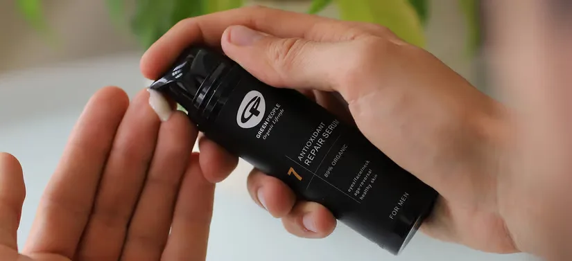 Her ses hænderne af en person, som er ved at få noget produkt ud af en sort Green People vare.