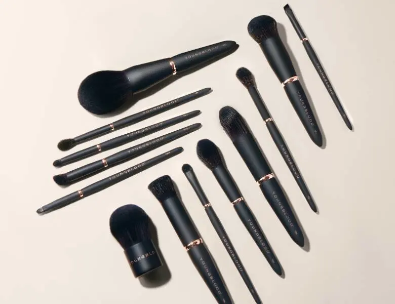 Her ses mange forskellige makeupbørster, som alle er sorte, på en lys baggrund. 
