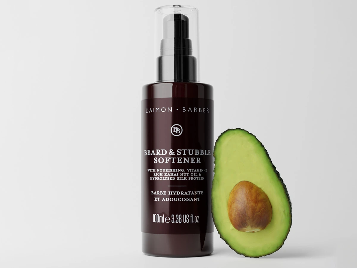 Daimon Barber Beard & Stubble Softener. Med nærende, E-vitaminrig Kahai Nøddeolie og hydrolyseret silkeprotein. Fugtgivende og blødgørende skæg. 100ml 3.38 US fl.oz. En halv avocado er placeret ved siden af.