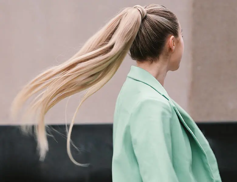 Her ses en kvinde med en meget lang og tyk hestehale. Hun er udenfor og har en grøn blazer på.