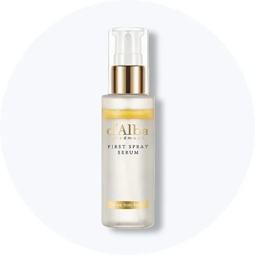 Her ses et d'Alba First Spray Serum i en hvid sprayflaske med gulddetaljer på en lys baggrund.