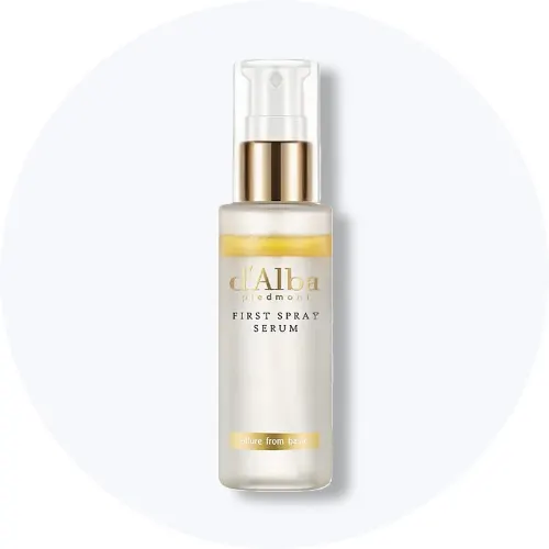 Her ses et d'Alba First Spray Serum i en hvid sprayflaske med gulddetaljer på en lys baggrund.