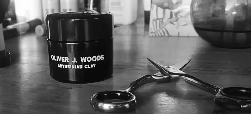 Her ses Oliver J Woods produkter på et mørkt bord.