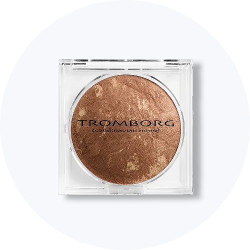 Her ses en Tromborg bronzer i en rund, brun nuance med marmoreret overflade, placeret i en transparent, firkantet beholder. På produktet står “Tromborg Scandinavian Mood”.