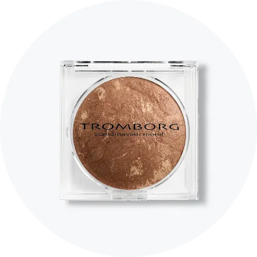Her ses en Tromborg bronzer i en rund, brun nuance med marmoreret overflade, placeret i en transparent, firkantet beholder. På produktet står “Tromborg Scandinavian Mood”.