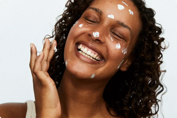 Her ses en glad kvinde med creme-pletter i ansigtet. Baggrunden er lys.