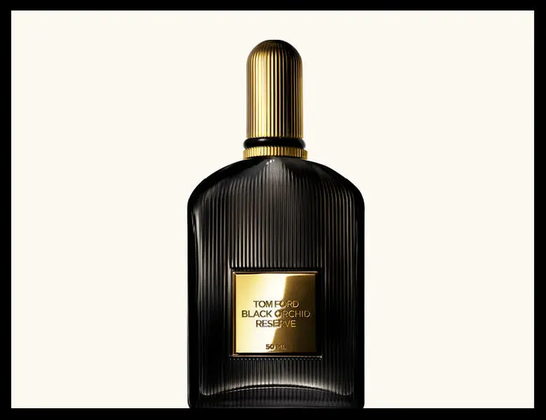 Her ses en sort parfumeflakon med guldlåg på en beige baggrund. Rundt om er en sort ramme.