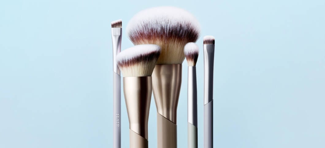 Her ses spidsen af fem makeupbørster i forskellge størrelser på en blå baggrund.