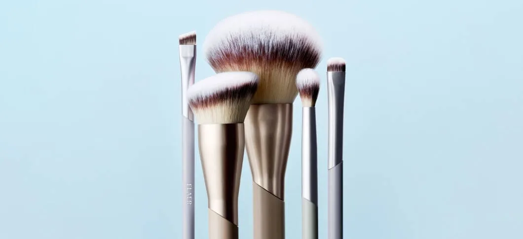 Her ses spidsen af fem makeupbørster i forskellge størrelser på en blå baggrund.