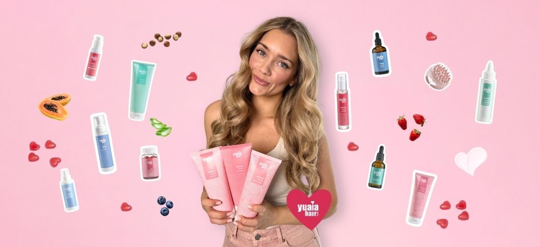 Her ses en kvinde, der holder Yuaia Hair produkter omgivet af små produktikoner og frugter på en lyserød baggrund.