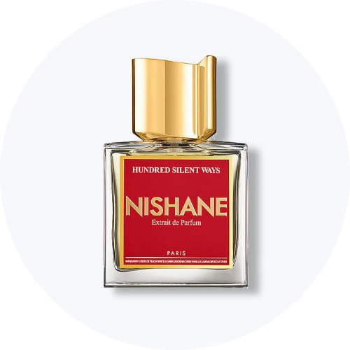 Her ses et billede af en parfumeflakon fra Nishane placeret centralt mod en lys, rund baggrund. På flakonen står teksten “HUNDRED SILENT WAYS NISHANE Extrait de Parfum”. Flakonen er i klart glas med rød label og guldfarvet låg.