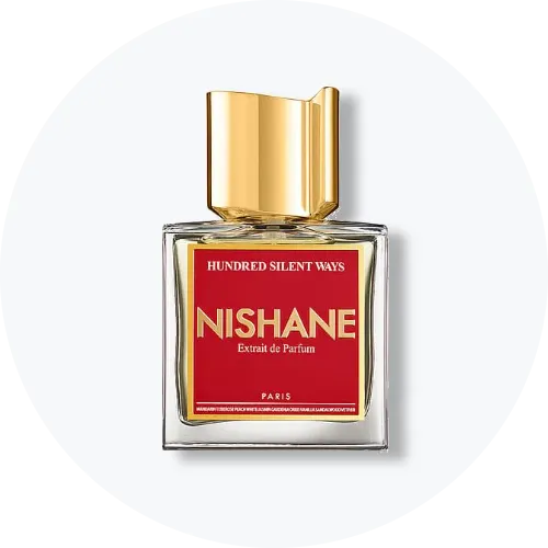 Her ses et billede af en parfumeflakon fra Nishane placeret centralt mod en lys, rund baggrund. På flakonen står teksten “HUNDRED SILENT WAYS NISHANE Extrait de Parfum”. Flakonen er i klart glas med rød label og guldfarvet låg.