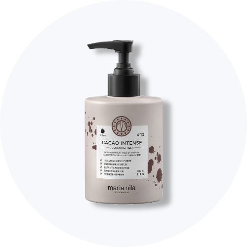 Her ses et billede af et hårplejeprodukt fra Maria Nila placeret centralt mod en lys, rund baggrund. På flasken står teksten “CACAO INTENSE Colour Refresh”. Flasken er i lysegrå nuance med sort pumpe og brune detaljer på etiketten.