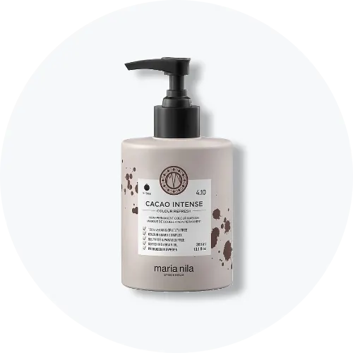 Her ses et billede af et hårplejeprodukt fra Maria Nila placeret centralt mod en lys, rund baggrund. På flasken står teksten “CACAO INTENSE Colour Refresh”. Flasken er i lysegrå nuance med sort pumpe og brune detaljer på etiketten.