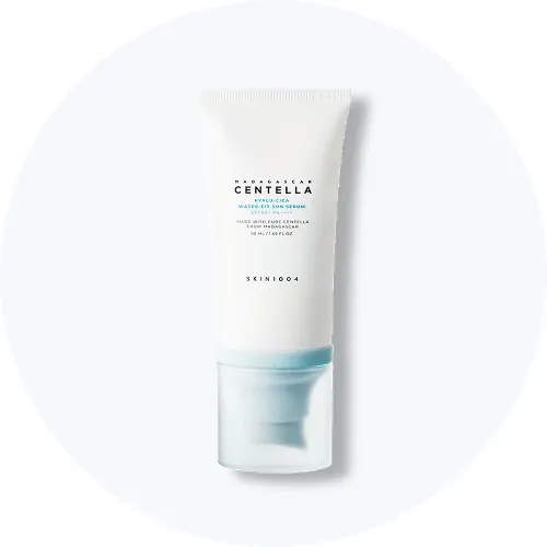 Her ses en SKIN1004 Madagascar Centella Hyalu-Cica Water-Fit Sun Serum SPF 50+ i hvid emballage med lyseblå detaljer på en lys baggrund.