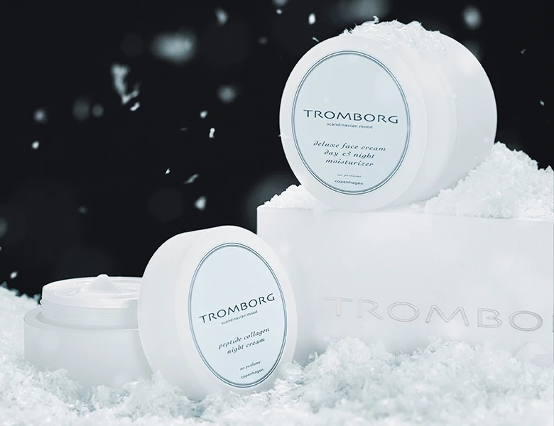 To hvide Tromborg cremekrukker, deluxe ansigtscreme og peptid kollagen natcreme, i sneklædte omgivelser.
