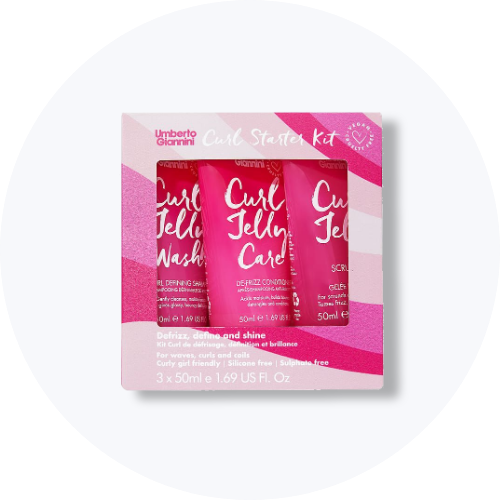Her ses et billede af et produktkit med flere hårprodukter placeret centralt mod en lys baggrund. Pakken indeholder små tuber med teksten “Curl Jelly Wash” og “Curl Jelly Care” i pink emballage.