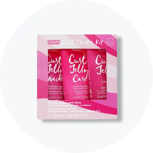 Her ses et billede af et produktkit med flere hårprodukter placeret centralt mod en lys baggrund. Pakken indeholder små tuber med teksten “Curl Jelly Wash” og “Curl Jelly Care” i pink emballage.