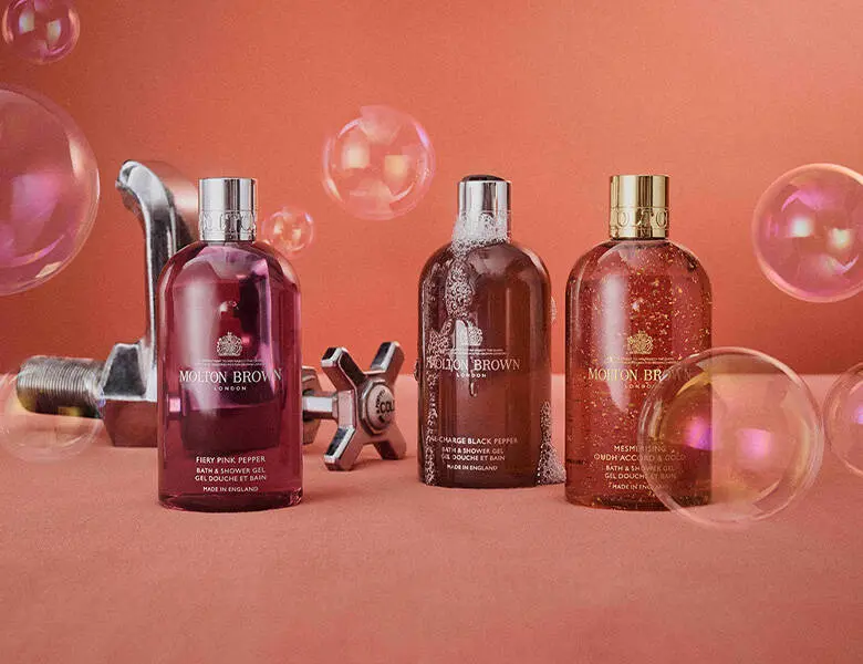 Her ses tre rødlige produkter fra Molton Brown. Baggrunden er rød og har sæbebobler flyvende rundt. 