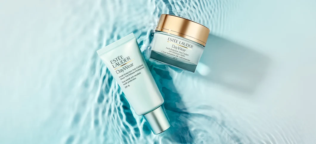 Her ses et billede med hudplejeprodukter fra Estée Lauder placeret over en vandinspireret baggrund. På produkterne står teksten “DayWear”, og emballagen er i lyseblå og gyldne nuancer.