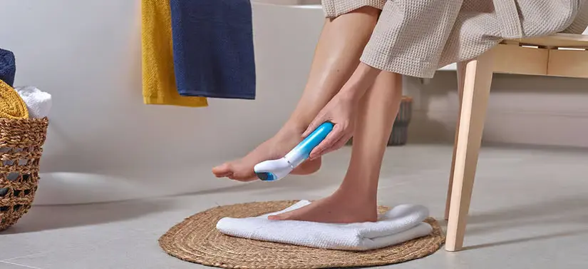 Her ser man en kvinde, som sidder på en skammel på badeværelsen. Hun bruger et Scholl produkt på fødderne. 
