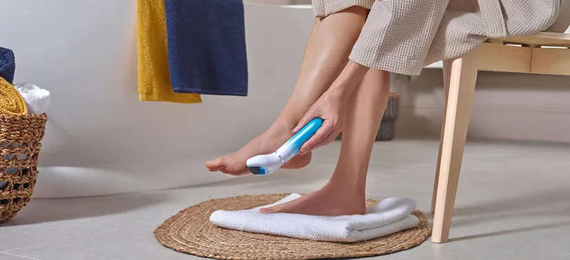 Her ser man en kvinde, som sidder på en skammel på badeværelsen. Hun bruger et Scholl produkt på fødderne. 
