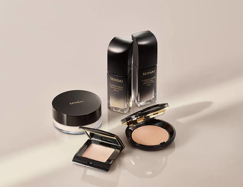 Her ses en lys baggrund med flere sorte makeupprodukter. 