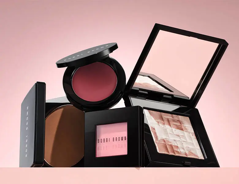 Her ses en sart lyserød baggrund med forskellige makeupprodukter.
