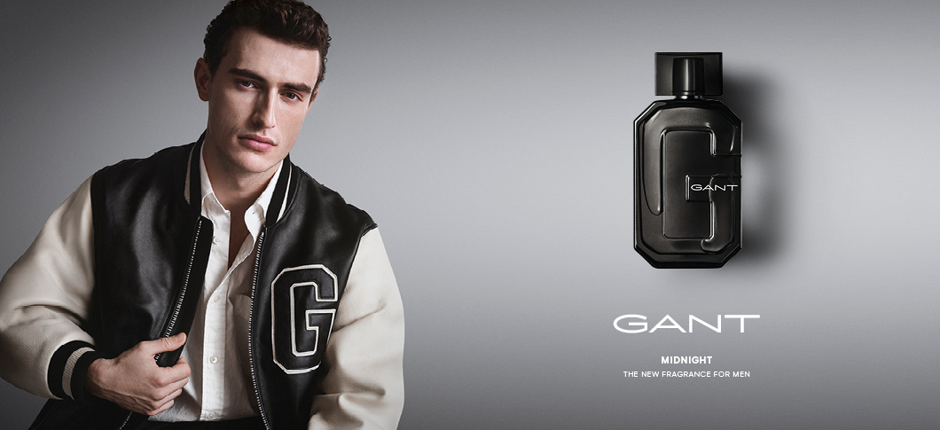 Her ses et billede med en person til venstre iført en jakke med et “G” på brystet mod en lys baggrund samt en parfumeflakon til højre. På billedet står teksten “GANT”, “MIDNIGHT” og “THE NEW FRAGRANCE FOR MEN”. Flakonen har teksten “GANT” på fronten.