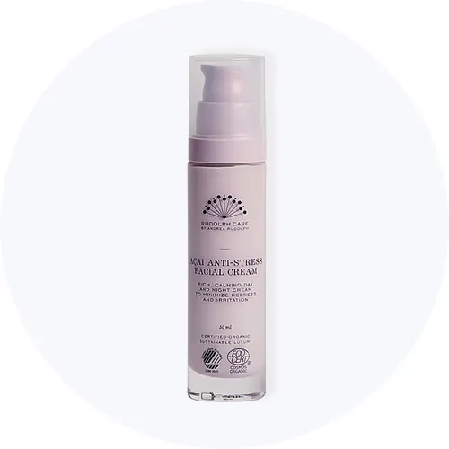 Her ses Rudolph Care Acai Anti-Stress Facial Cream i en lyserød flaske med pumpe på en lysegrå cirkel.